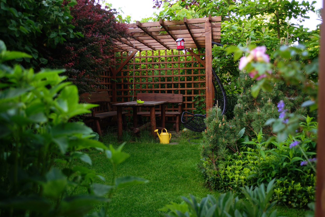 A wooden gazebo tucked away in a tropical backyard garden.