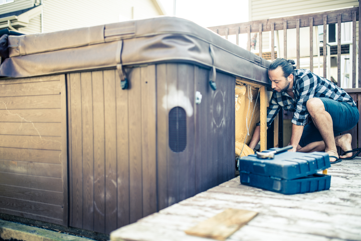 Man is repairing an outdoor hot tub.