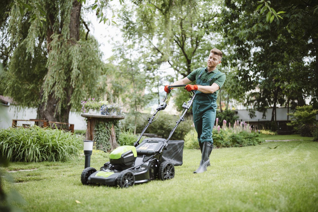 A man pushes a lawn mower to mow grass.